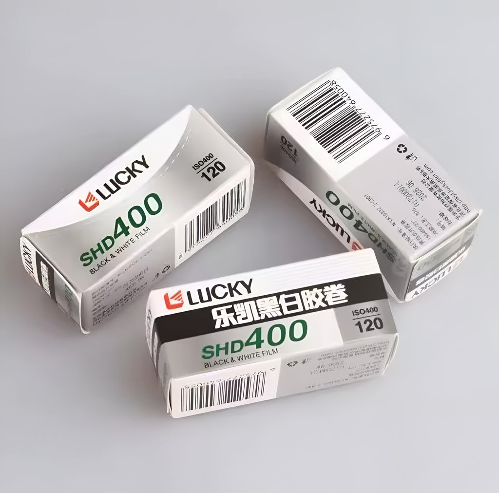Three boxes of Lucky SHD400 black and white film on a gray background